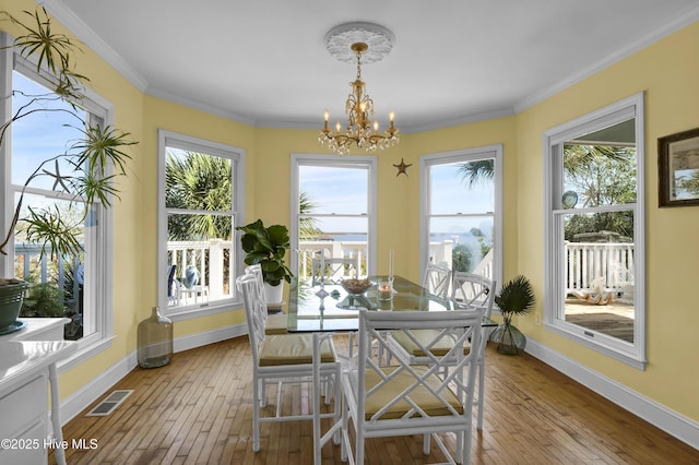 dining area with an inviting chandelier, crown molding, and light wood-type flooring