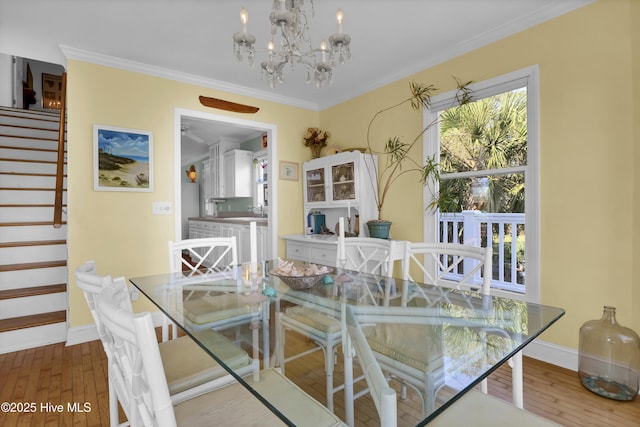 dining room featuring sink, crown molding, wood-type flooring, and a chandelier