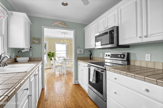 kitchen featuring appliances with stainless steel finishes, tile counters, sink, and white cabinets