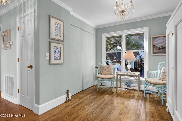 living area featuring wood-type flooring, ornamental molding, and an inviting chandelier