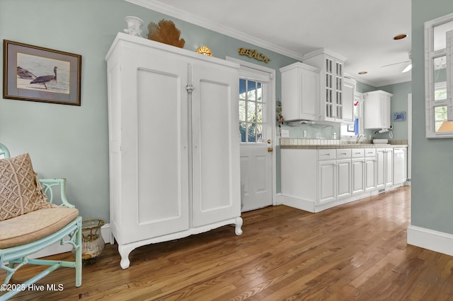 kitchen with hardwood / wood-style flooring, crown molding, sink, and white cabinets