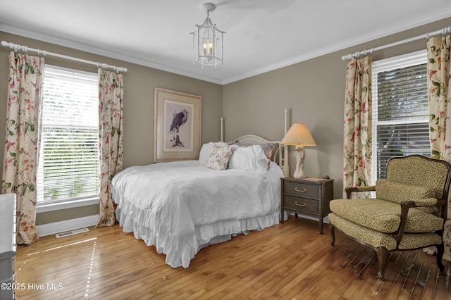 bedroom featuring light hardwood / wood-style flooring, ornamental molding, and a chandelier