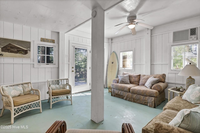 living room with a wall unit AC and ceiling fan