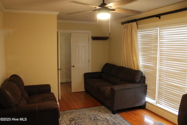 living room with ornamental molding, wood-type flooring, and ceiling fan