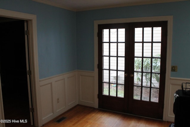 entryway featuring crown molding, light hardwood / wood-style floors, and french doors