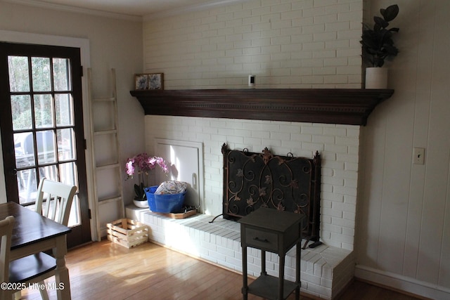 room details with ornamental molding, a brick fireplace, and hardwood / wood-style floors