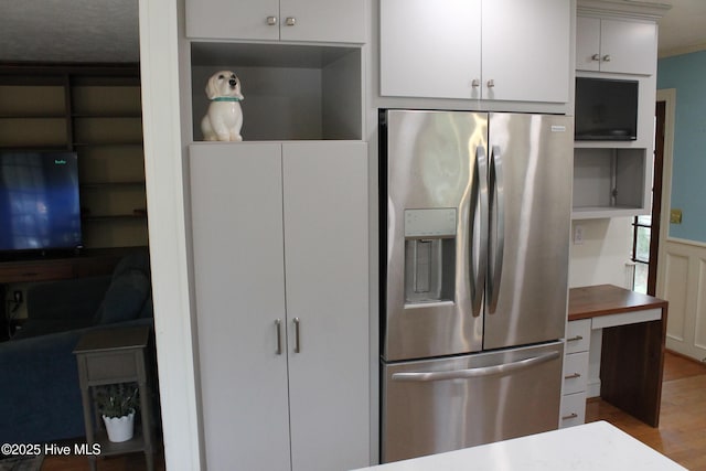 kitchen with light hardwood / wood-style flooring, built in shelves, stainless steel fridge, and white cabinets