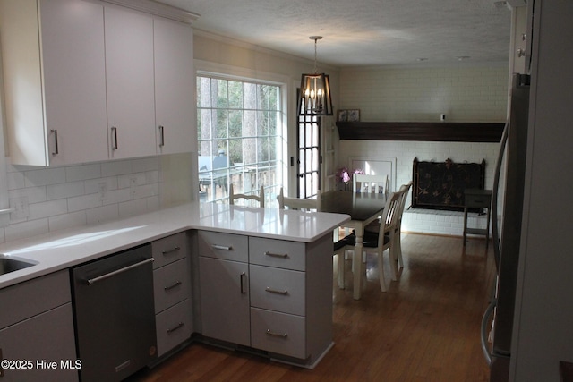 kitchen featuring appliances with stainless steel finishes, hanging light fixtures, backsplash, dark hardwood / wood-style floors, and kitchen peninsula