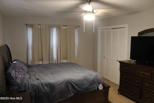 bedroom with ceiling fan, light colored carpet, and a closet