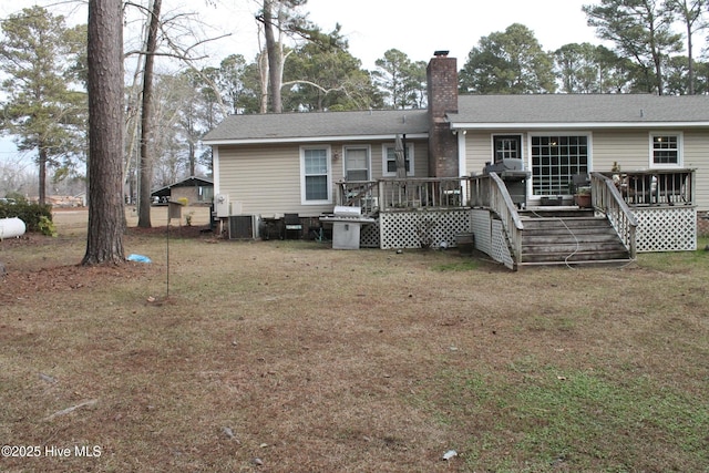 rear view of property with a wooden deck and a lawn