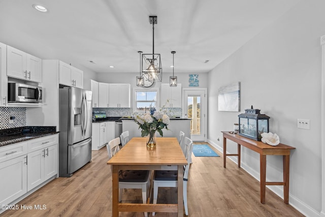 kitchen with white cabinetry, hanging light fixtures, backsplash, and appliances with stainless steel finishes