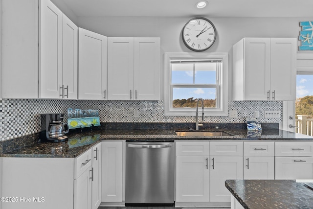 kitchen featuring sink, stainless steel dishwasher, dark stone counters, and white cabinets