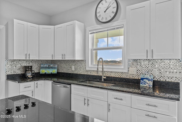 kitchen featuring sink, white cabinetry, backsplash, stainless steel dishwasher, and dark stone counters