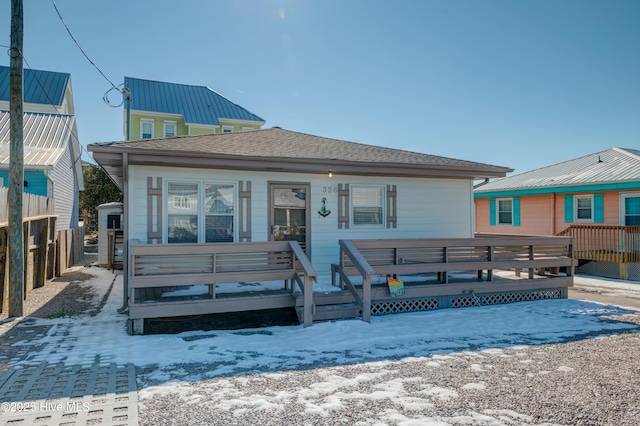 snow covered rear of property with a deck