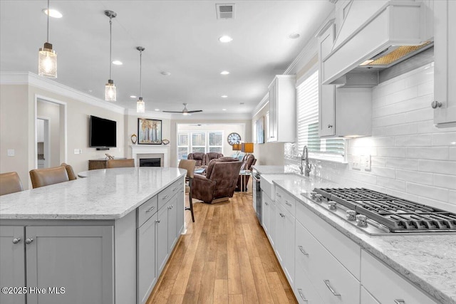 kitchen with premium range hood, a kitchen island, pendant lighting, a kitchen breakfast bar, and stainless steel appliances