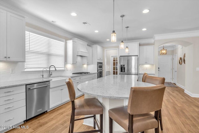 kitchen with appliances with stainless steel finishes, a center island, sink, and white cabinets