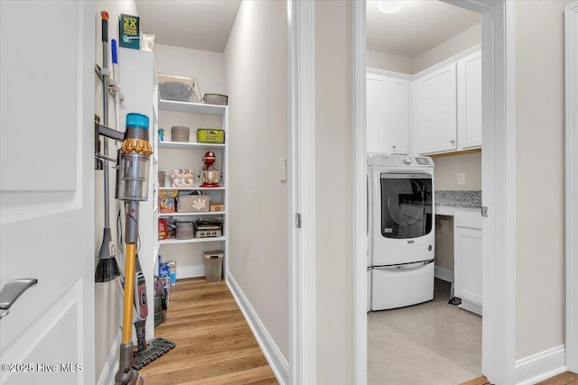 laundry area with cabinets, washer / dryer, and light wood-type flooring