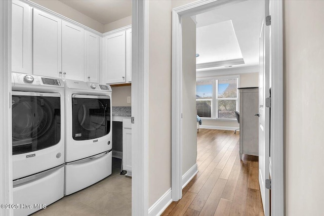 laundry area with cabinets, independent washer and dryer, and light hardwood / wood-style floors