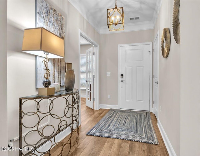 foyer featuring a notable chandelier, crown molding, and light wood-type flooring