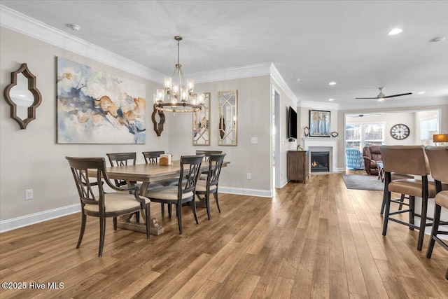 dining area with ornamental molding, ceiling fan with notable chandelier, and light hardwood / wood-style flooring