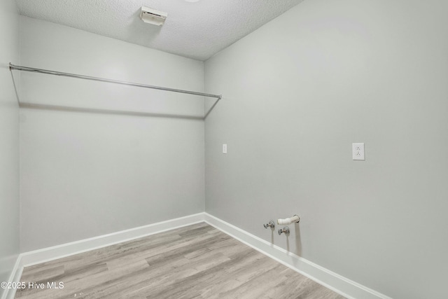 laundry area with light wood finished floors, hookup for a gas dryer, a textured ceiling, laundry area, and baseboards