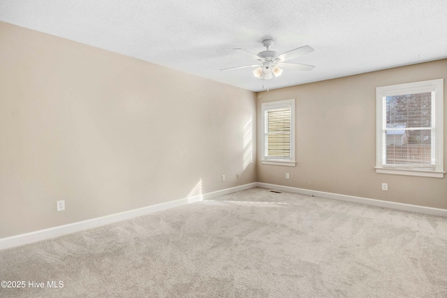 spare room with light carpet, ceiling fan, a textured ceiling, and baseboards