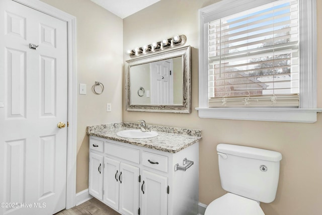 bathroom featuring baseboards, vanity, and toilet