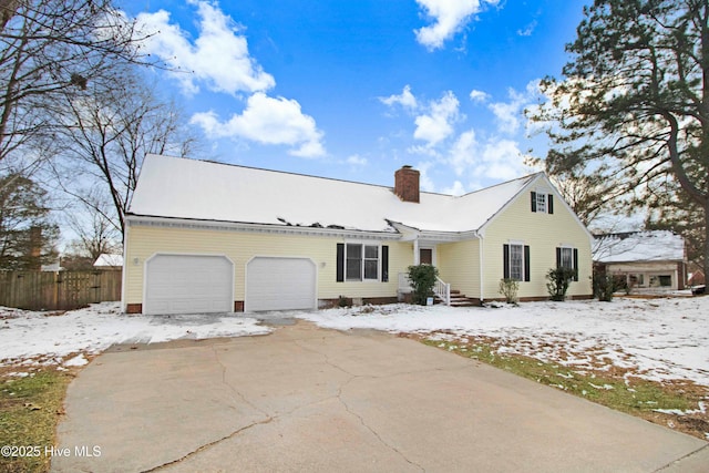 view of front of house featuring a chimney, fence, driveway, and an attached garage