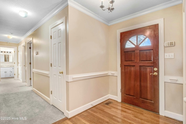 foyer featuring ornamental molding, visible vents, light wood-style flooring, and baseboards