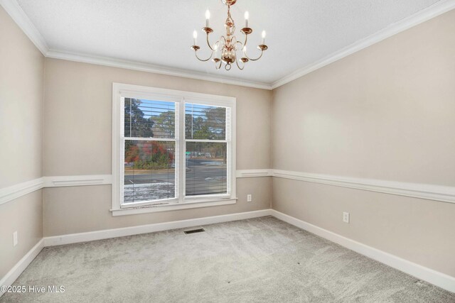 carpeted spare room with ornamental molding and a notable chandelier