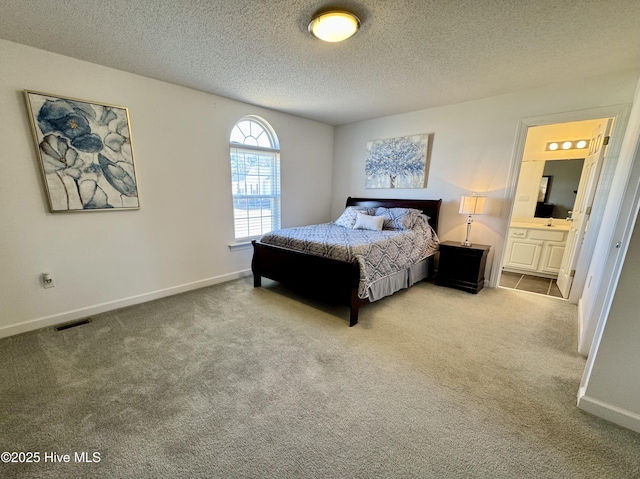 bedroom with light carpet, connected bathroom, and a textured ceiling