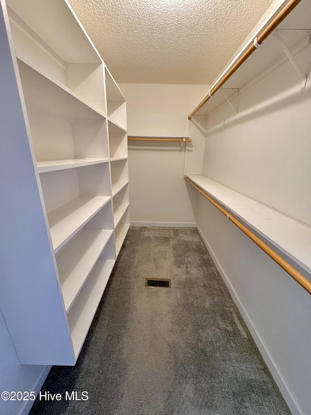 walk in closet featuring dark colored carpet