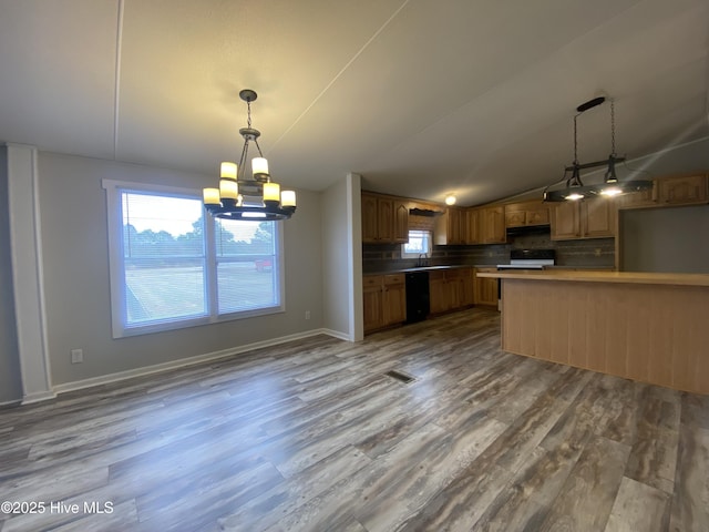 kitchen with decorative light fixtures, tasteful backsplash, black dishwasher, hardwood / wood-style flooring, and kitchen peninsula