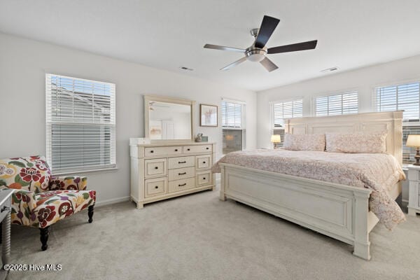 bedroom featuring ceiling fan, light carpet, and multiple windows