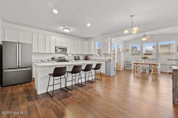 kitchen with decorative light fixtures, a center island, dark hardwood / wood-style floors, stainless steel appliances, and white cabinets