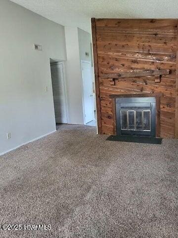 unfurnished living room with vaulted ceiling, carpet, and a textured ceiling