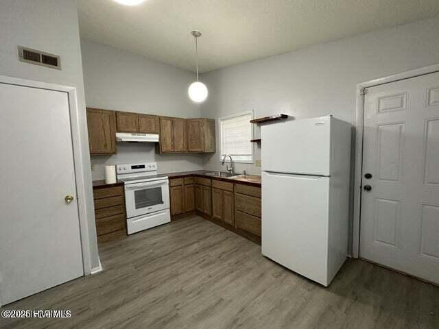 kitchen with hardwood / wood-style flooring, sink, pendant lighting, and white appliances