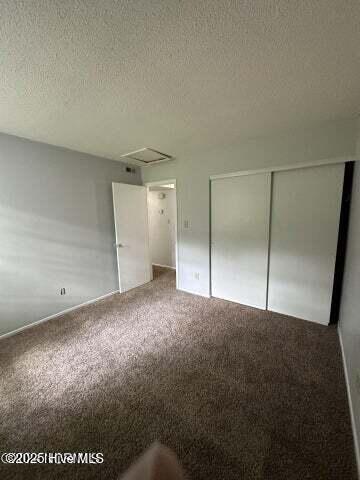 unfurnished bedroom featuring a closet, a textured ceiling, and carpet