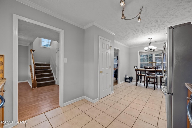 kitchen with crown molding, stainless steel fridge, a textured ceiling, and light tile patterned floors