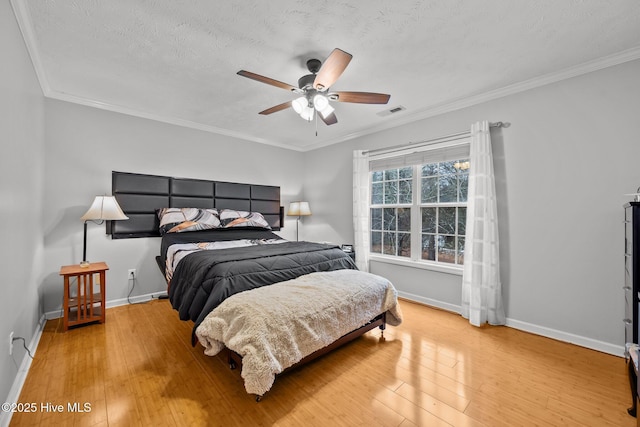 bedroom featuring ceiling fan, ornamental molding, light hardwood / wood-style flooring, and a textured ceiling