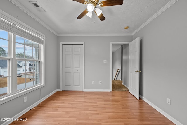 unfurnished bedroom with crown molding, a closet, ceiling fan, and light hardwood / wood-style flooring