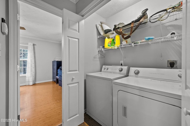 laundry area with ornamental molding, separate washer and dryer, and wood-type flooring