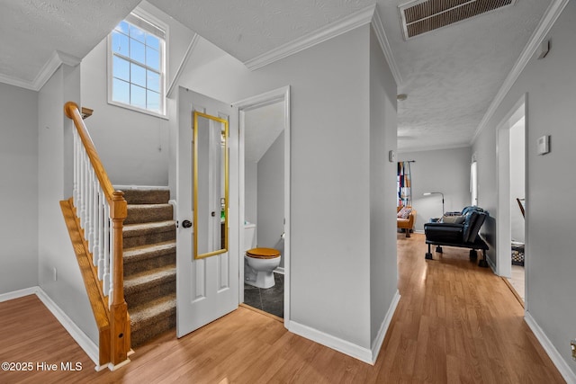 entrance foyer featuring ornamental molding, a textured ceiling, and light wood-type flooring