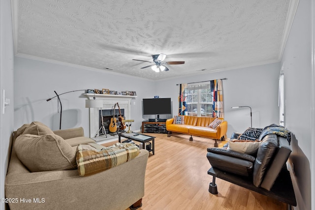 living room with crown molding, ceiling fan, hardwood / wood-style flooring, and a textured ceiling