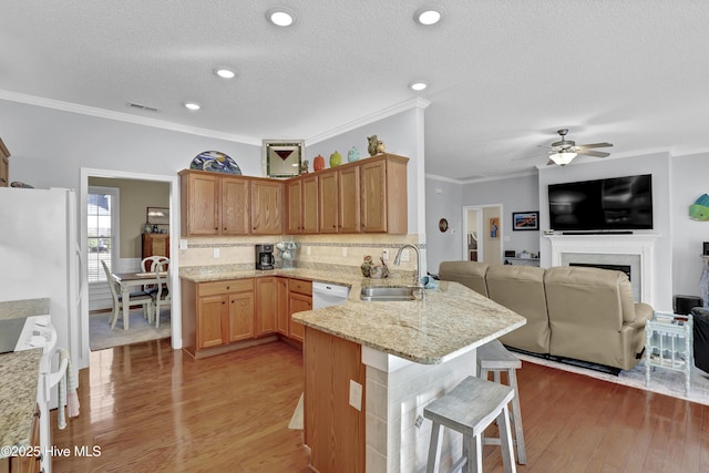 kitchen featuring sink, light hardwood / wood-style flooring, a kitchen breakfast bar, kitchen peninsula, and white appliances