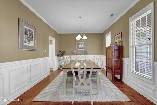 dining space with crown molding, dark hardwood / wood-style floors, and a chandelier