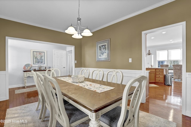 dining area with a notable chandelier, crown molding, and light hardwood / wood-style floors