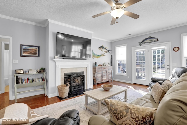 living room featuring ceiling fan, ornamental molding, hardwood / wood-style floors, and a textured ceiling