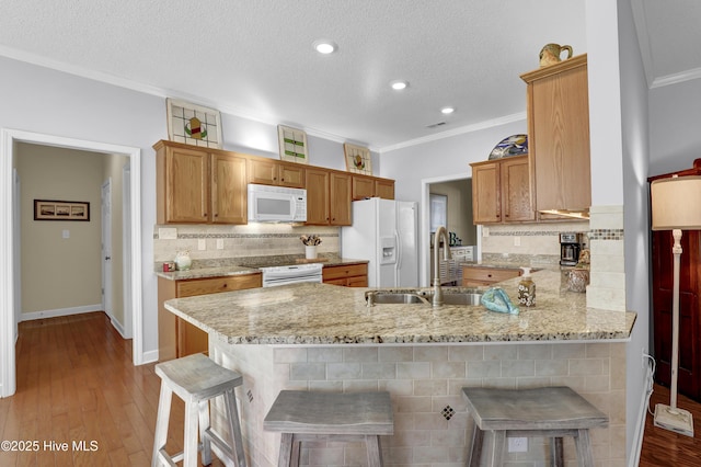 kitchen featuring sink, white appliances, kitchen peninsula, and a breakfast bar