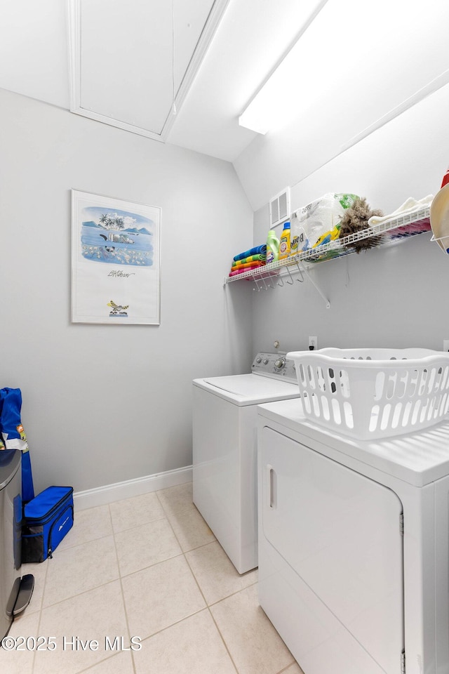 clothes washing area featuring light tile patterned floors and washer and clothes dryer